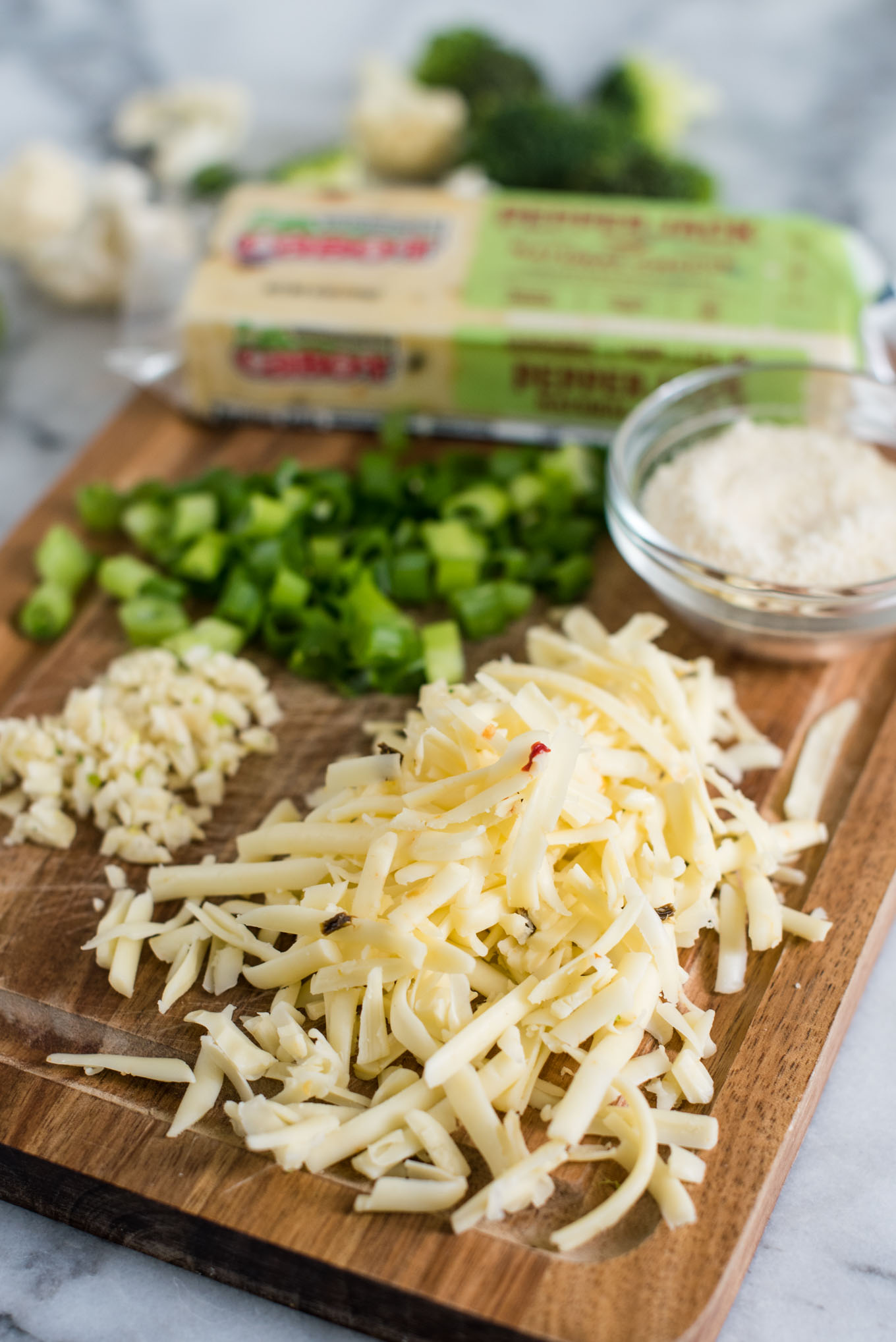 cutting board with cheese, garlic, green onions