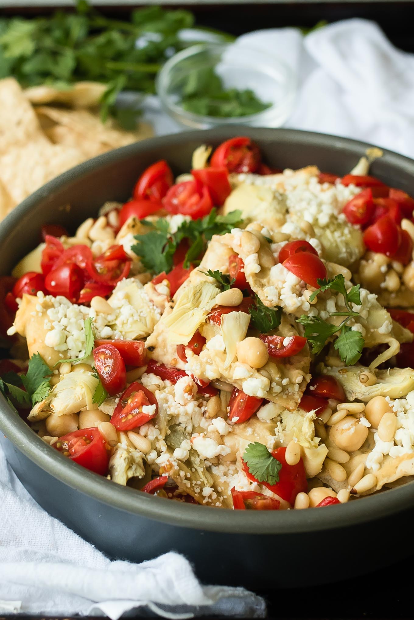 Mediterranean Nachos are a delicious gluten free and vegetarian snack/appetizer loaded with hummus, veggies, feta and more- a fun spin on the classic Tex Mex dish.