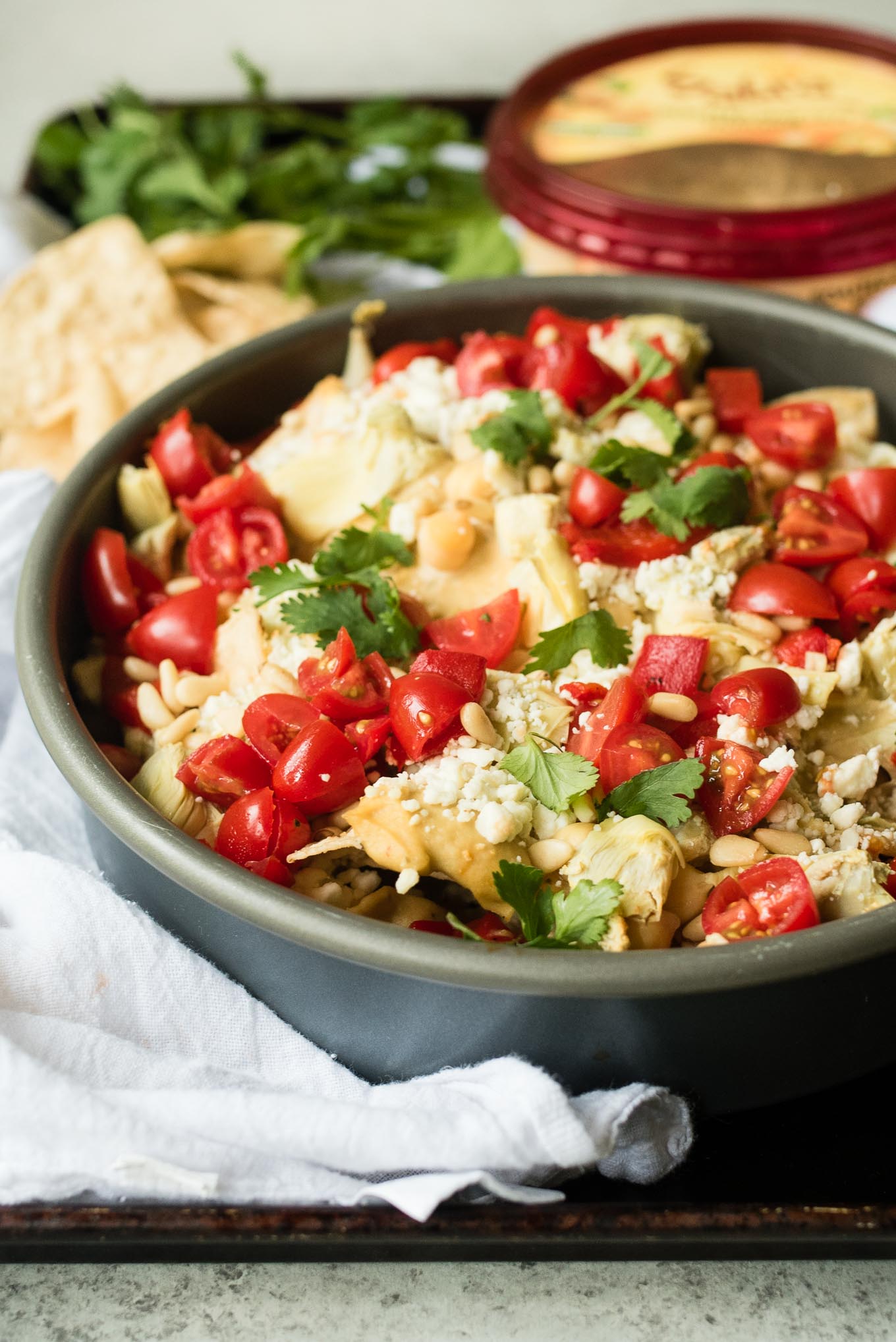 Mediterranean Nachos are a delicious gluten free and vegetarian snack/appetizer loaded with hummus, veggies, feta and more- a fun spin on the classic Tex Mex dish.