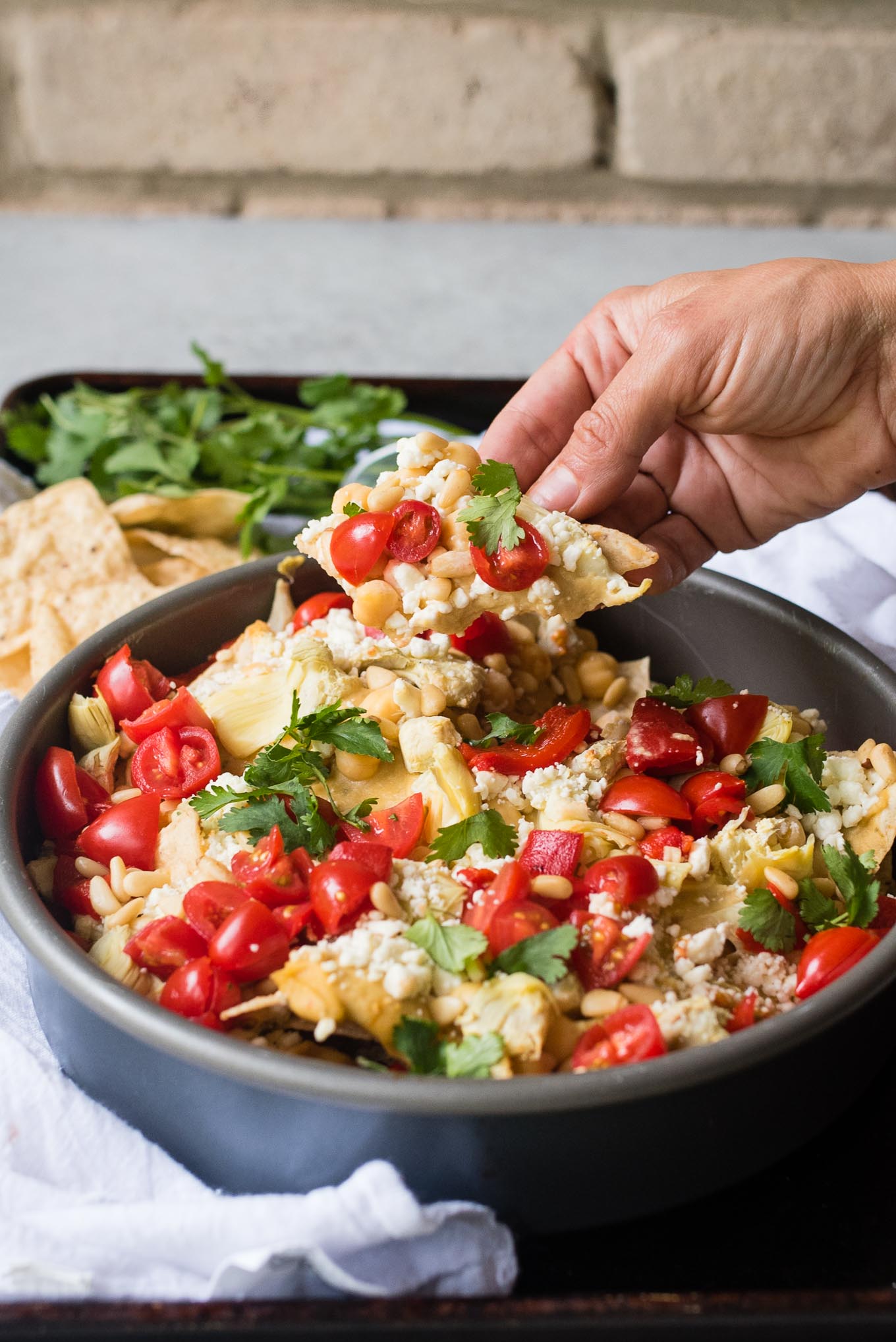 Mediterranean Nachos are a delicious gluten free and vegetarian snack/appetizer loaded with hummus, veggies, feta and more- a fun spin on the classic Tex Mex dish.